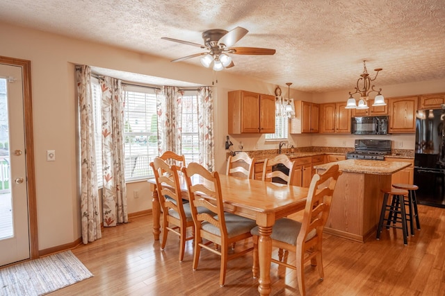 dining room featuring a textured ceiling, light wood-style flooring, a wealth of natural light, and a ceiling fan