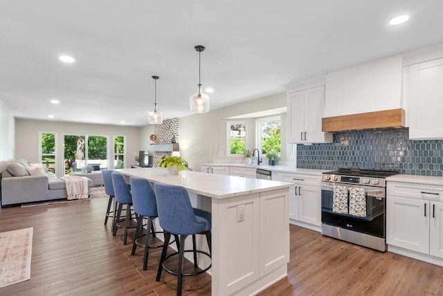 kitchen with stainless steel appliances, open floor plan, white cabinetry, backsplash, and a kitchen island