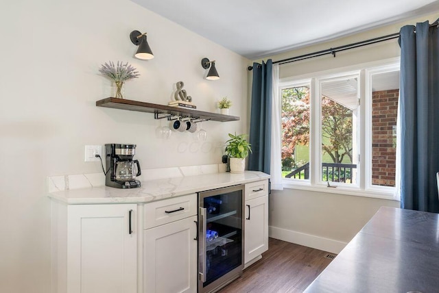 bar featuring beverage cooler, baseboards, wood finished floors, and a bar