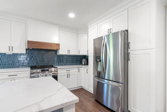 kitchen with appliances with stainless steel finishes, white cabinets, dark wood-style floors, and tasteful backsplash