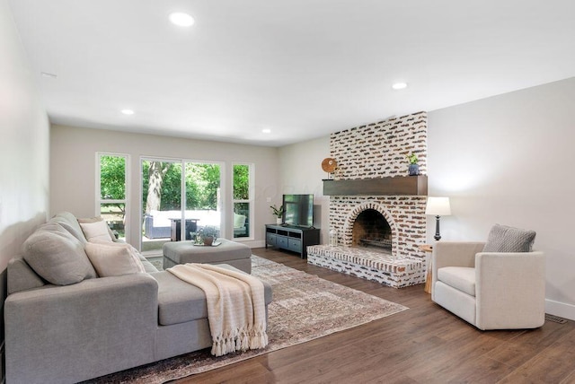 living area with a brick fireplace, recessed lighting, visible vents, and wood finished floors