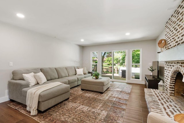 living area featuring a brick fireplace, recessed lighting, baseboards, and wood finished floors