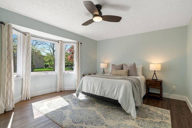 bedroom with a textured ceiling, baseboards, and wood finished floors