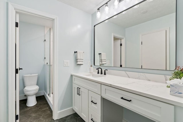 full bathroom featuring toilet, a stall shower, baseboards, and vanity