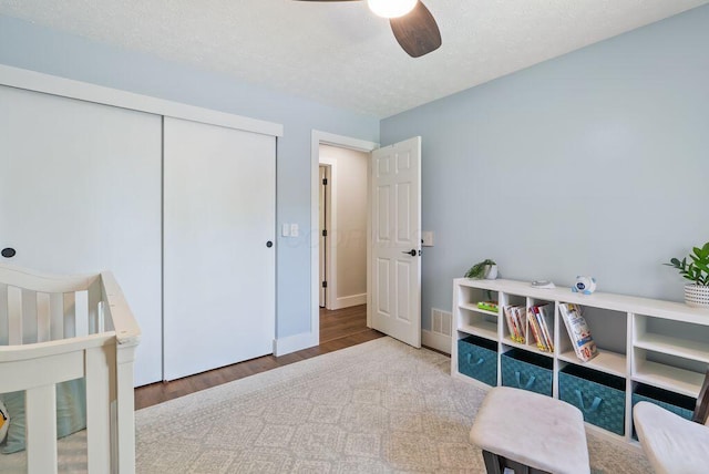 bedroom featuring a closet, visible vents, wood finished floors, a textured ceiling, and a ceiling fan