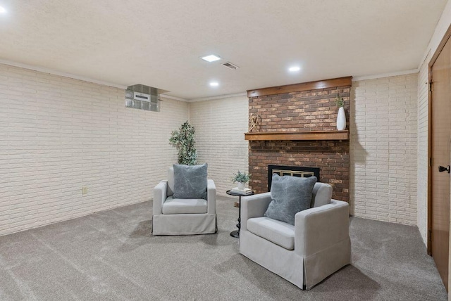 sitting room with crown molding, a brick fireplace, brick wall, carpet, and visible vents
