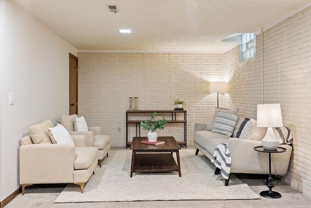 living area featuring carpet floors, baseboards, brick wall, and visible vents