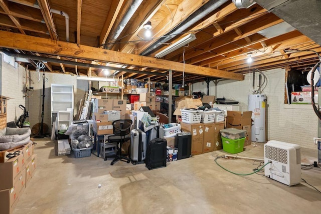 unfinished below grade area featuring water heater and brick wall