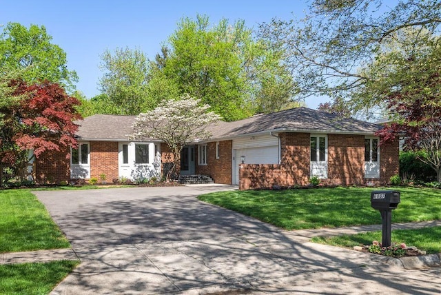 ranch-style home with an attached garage, concrete driveway, a front lawn, and brick siding
