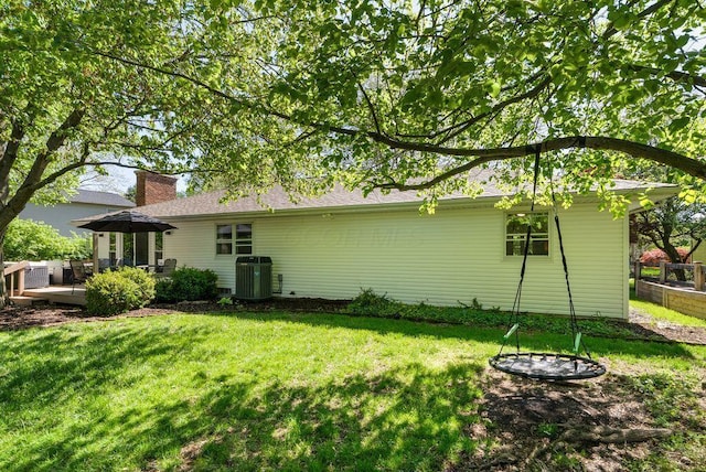 view of property exterior with a lawn, cooling unit, and a chimney