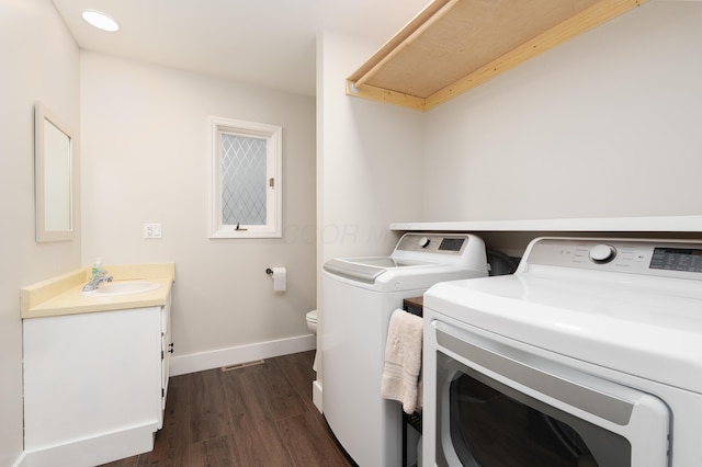 laundry area featuring laundry area, washing machine and dryer, baseboards, dark wood-style floors, and a sink