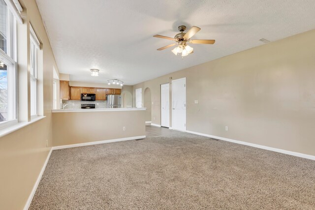 577 Stable St, Pataskala, OH 43062 - unfurnished living room with a ceiling fan, dark carpet, a textured ceiling, baseboards, and arched walkways