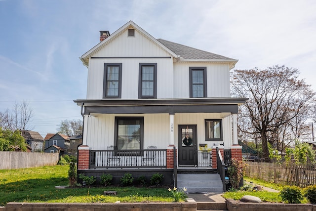 view of front facade featuring a porch, a front yard, fence, and a chimney