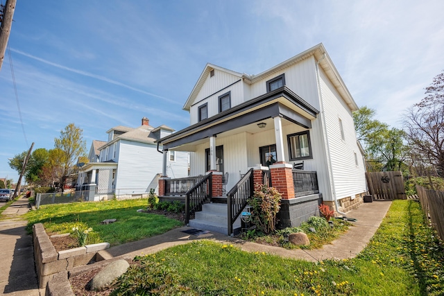 view of front of property with fence, a porch, and a front lawn