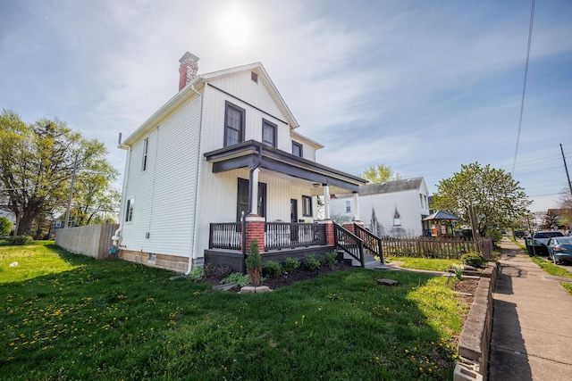 view of front of house with a porch, a front lawn, and a chimney