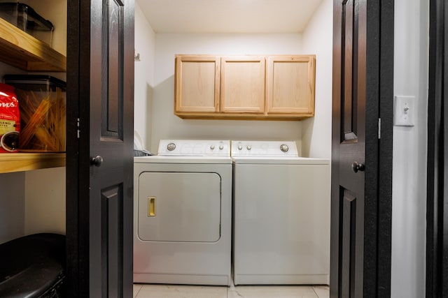 clothes washing area featuring light tile patterned floors, cabinet space, and washing machine and clothes dryer