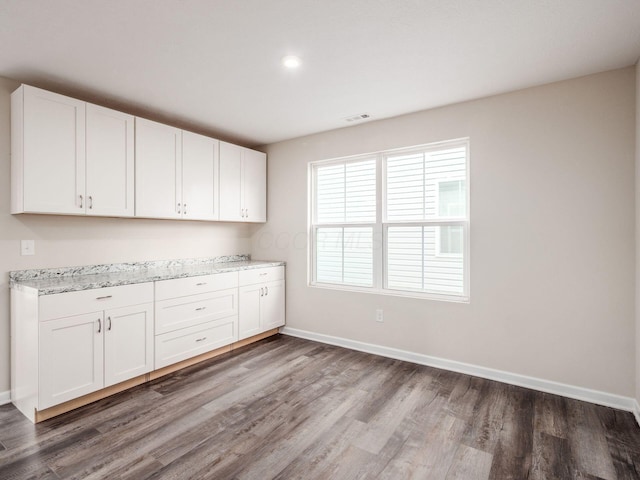 interior space featuring white cabinets, wood finished floors, visible vents, and baseboards