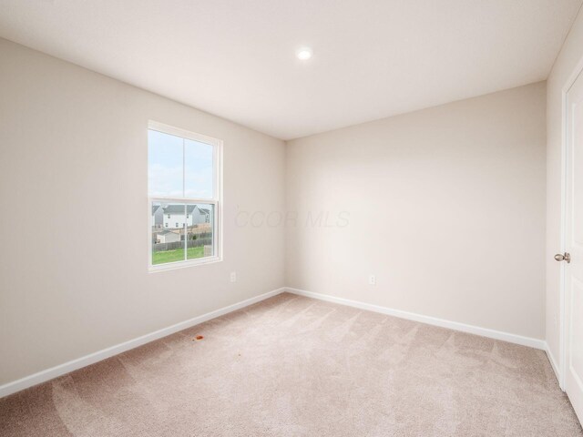 spare room with baseboards, recessed lighting, and light colored carpet