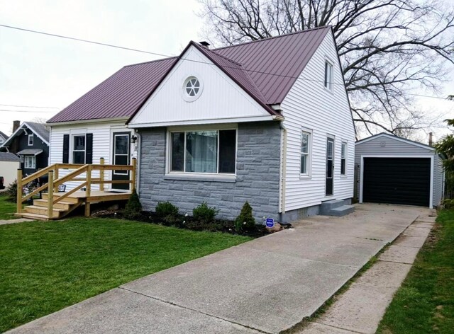 bungalow-style house with a front lawn, a detached garage, driveway, stone siding, and an outdoor structure