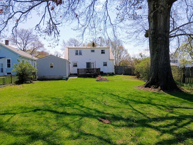 back of property with a fenced backyard, a deck, and a lawn