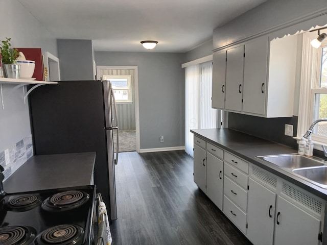 kitchen with dark wood-type flooring, dark countertops, a healthy amount of sunlight, and range with electric stovetop