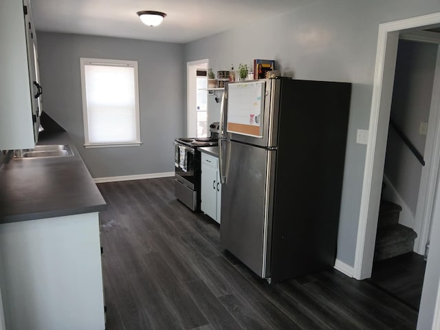 kitchen featuring stainless steel appliances, dark countertops, dark wood-type flooring, baseboards, and white cabinetry