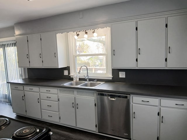 kitchen with dark countertops, dishwasher, a sink, and plenty of natural light