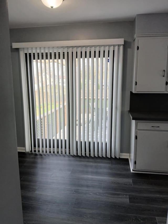 unfurnished dining area featuring plenty of natural light, baseboards, and dark wood-style floors