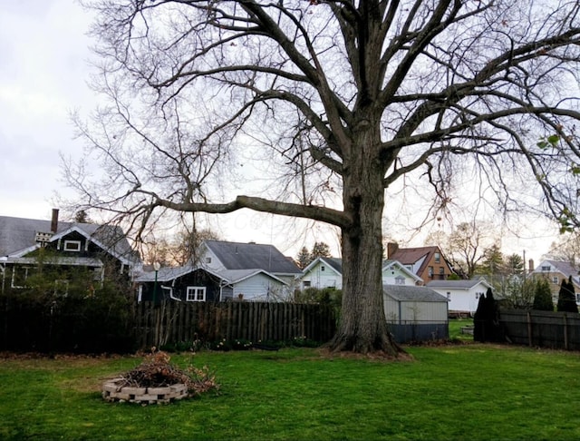 view of yard featuring fence, a fire pit, and a residential view