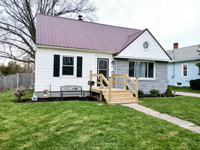 bungalow with metal roof, stone siding, a front yard, and fence