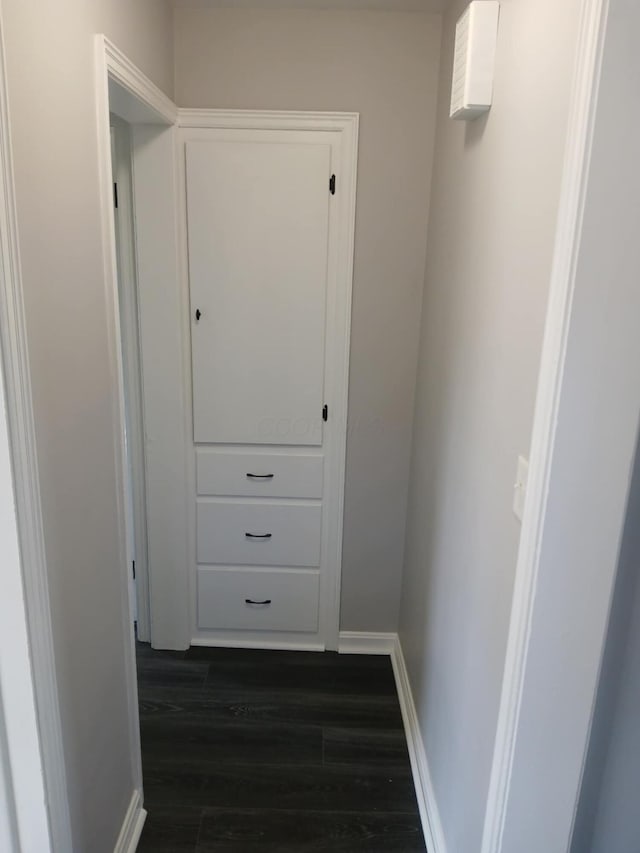 hall with baseboards and dark wood-type flooring