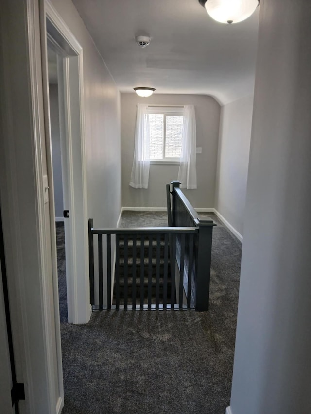 hall with carpet, lofted ceiling, baseboards, and an upstairs landing