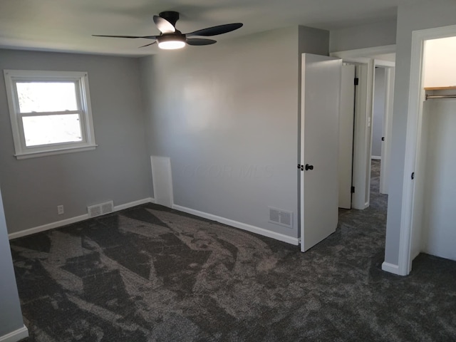 carpeted spare room featuring baseboards, visible vents, and ceiling fan
