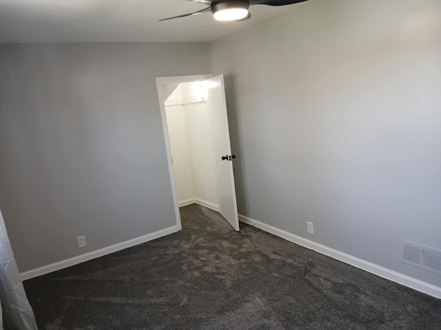 spare room featuring baseboards, a ceiling fan, visible vents, and dark colored carpet