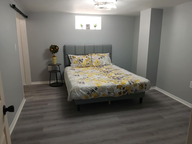 bedroom featuring a barn door, wood finished floors, and baseboards