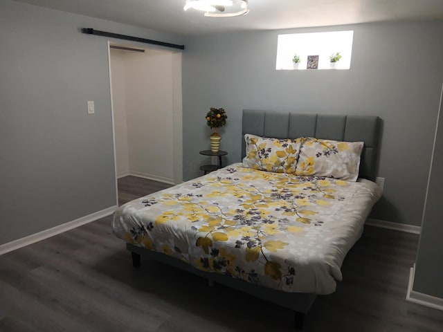bedroom featuring a barn door, wood finished floors, and baseboards