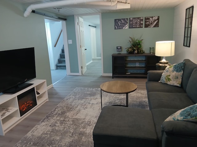 living area with baseboards, wood finished floors, and stairs