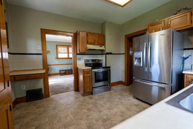 317 N High St, New Lexington, OH 43764 - kitchen with appliances with stainless steel finishes, under cabinet range hood, brown cabinetry, light countertops, and tile walls