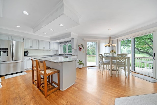 6180 Storm Haven Ct, Lewis Center, OH 43035 - kitchen featuring stainless steel refrigerator with ice dispenser, crown molding, light wood-type flooring, a kitchen island, and light stone countertops