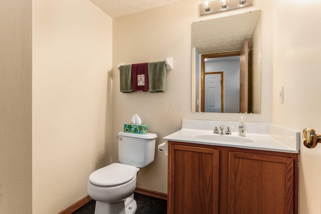 half bath with vanity, baseboards, toilet, and a textured ceiling