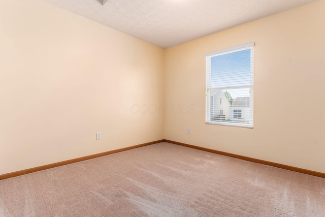 carpeted spare room with baseboards and a textured ceiling