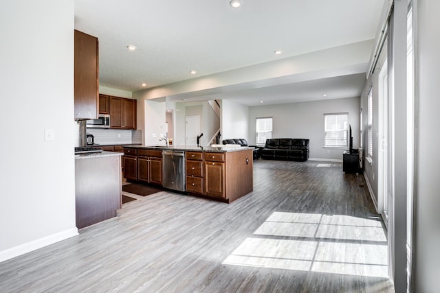 kitchen with wood finished floors, open floor plan, stainless steel appliances, baseboards, and recessed lighting