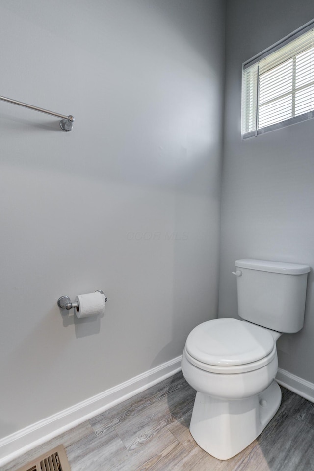 bathroom with baseboards, toilet, and wood finished floors