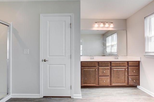 bathroom with wood finished floors, a sink, a shower stall, and a healthy amount of sunlight