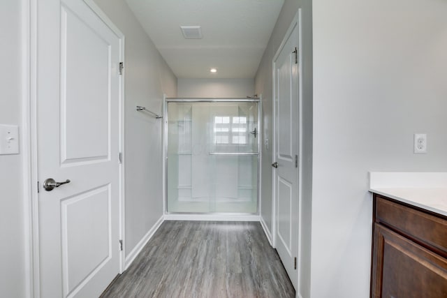 full bathroom featuring baseboards, wood finished floors, vanity, and a stall shower