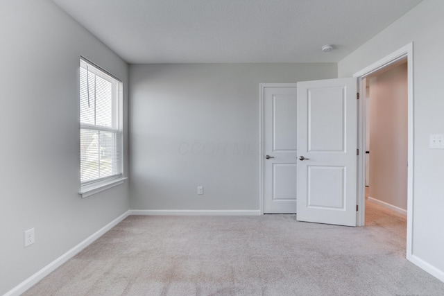 spare room featuring plenty of natural light, carpet flooring, and baseboards
