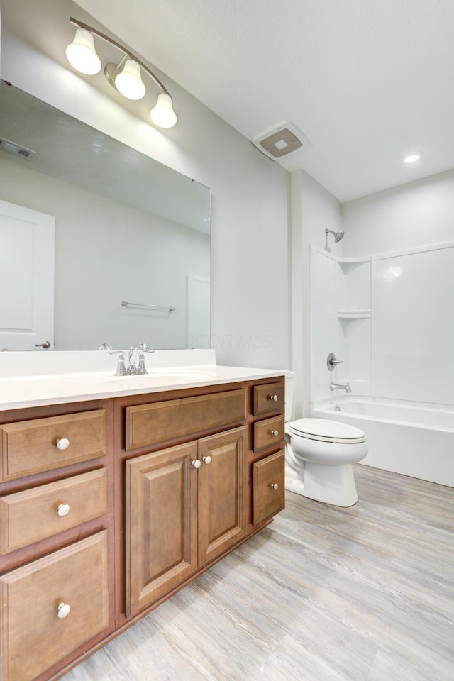 full bathroom featuring  shower combination, toilet, visible vents, wood finished floors, and vanity