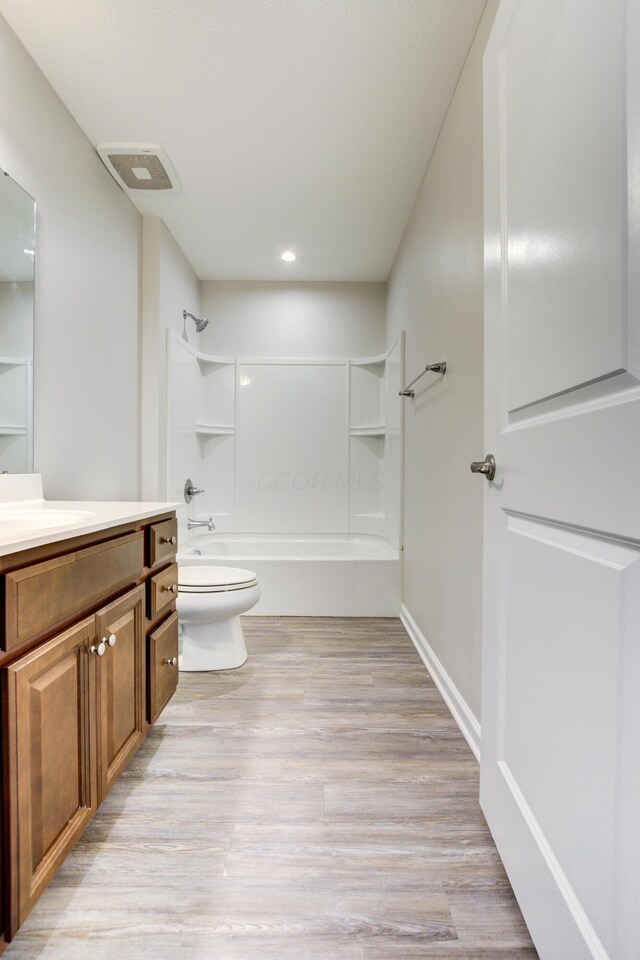 bathroom featuring wood finished floors, vanity, washtub / shower combination, toilet, and visible vents
