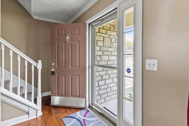 foyer entrance with plenty of natural light, wood finished floors, ornamental molding, and stairs