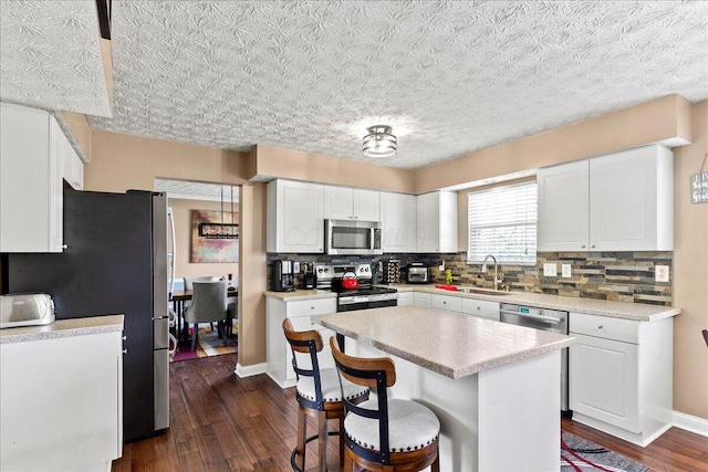 kitchen featuring a sink, dark wood finished floors, white cabinetry, appliances with stainless steel finishes, and tasteful backsplash